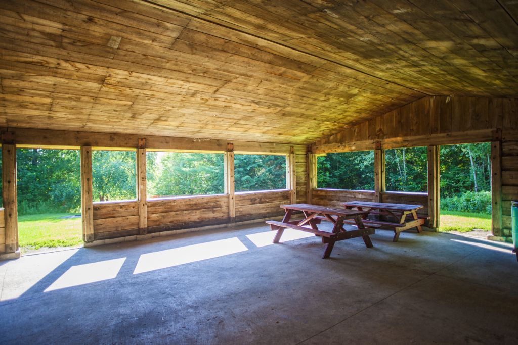 Interior view of the Scanlon Creek North Pavilion featuring open wooden structure, concrete pad, picnic tables and ample space to gather.