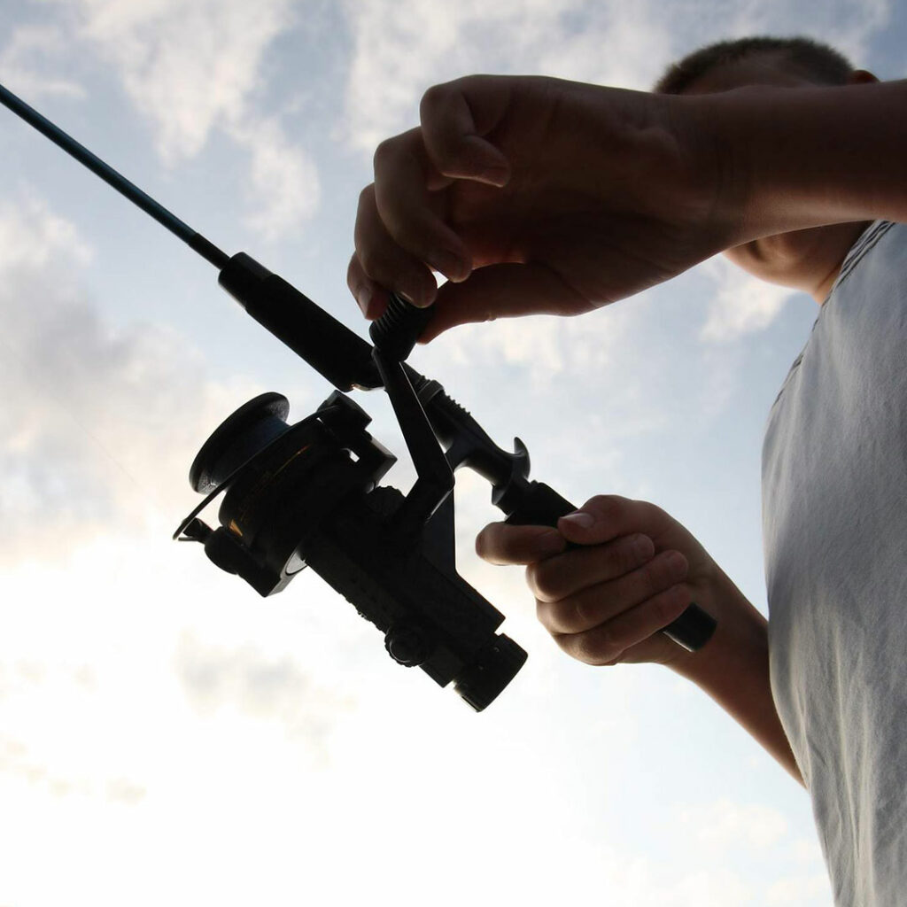A close up of someone holding a fishing rod on a cloudy warm day.
