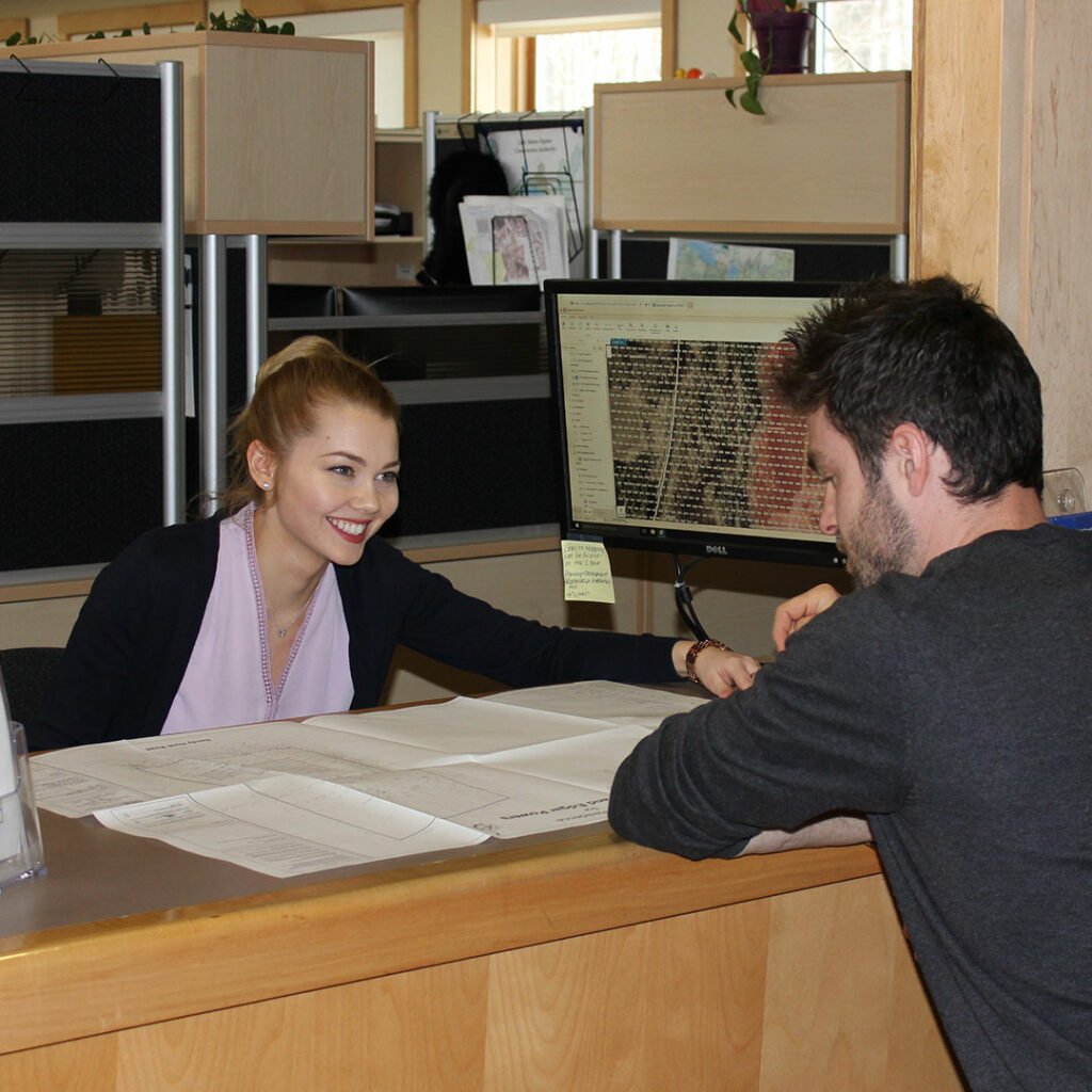 Conservation Authority staff sitting at the planning counter pointing to a map on the table and smiling.