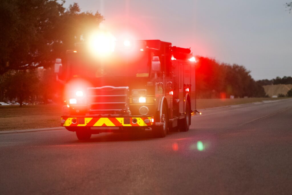A fire truck with its lights on driving down the road in the evening