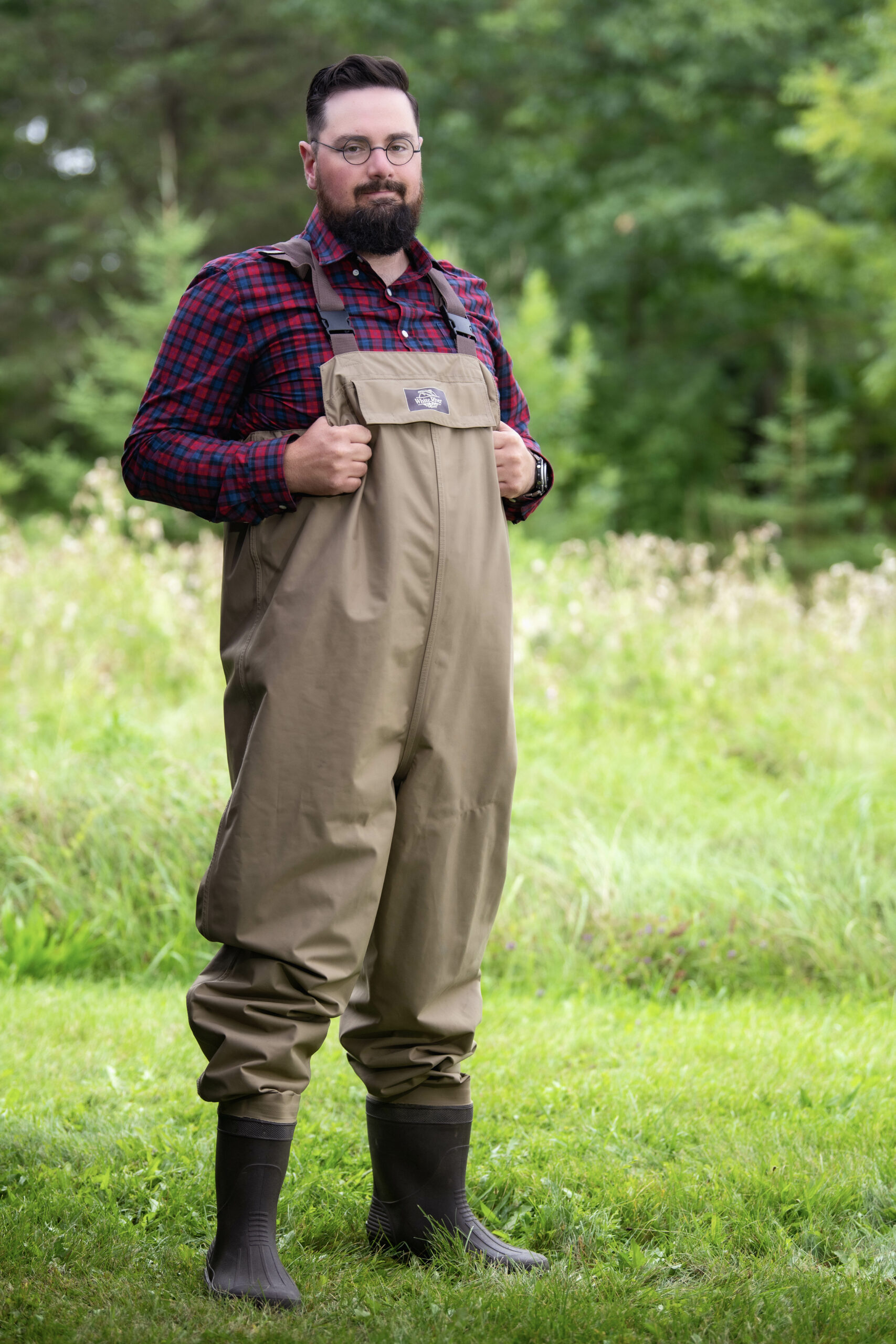 Ray Bolton standing in hip waders in the grass on a sunny day